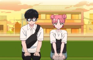 アニメ「正反対な君と僕」のワンシーン。夕暮れ時の屋上で、少し距離を置いて座る眼鏡姿の谷くんとピンクのお団子ヘアの鈴木。二人の初々しい空気感と背景の柔らかな夕景。